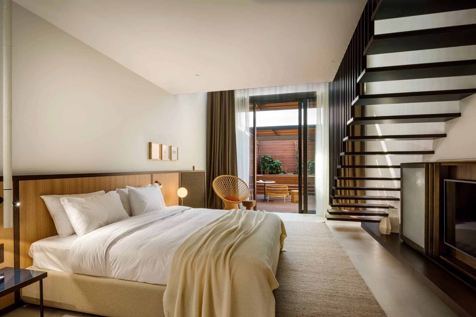 cream colored bed with stairs leading up and sliding glass door to terrace