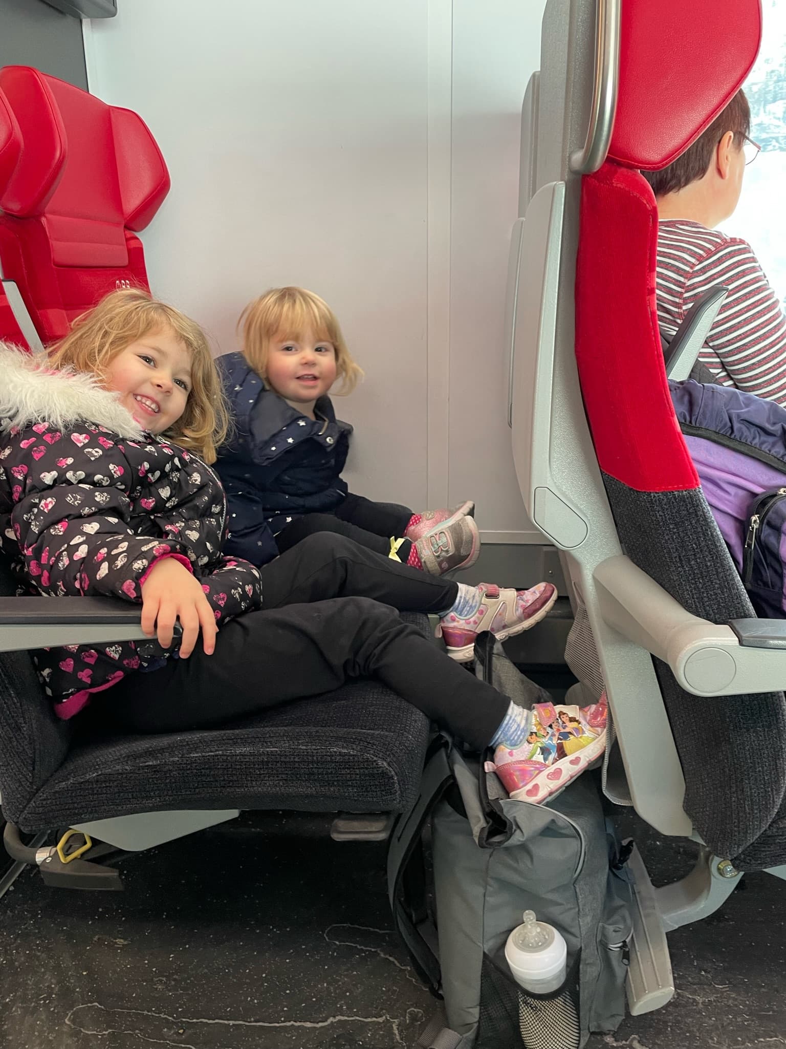 Kids posing in red airplane seats.