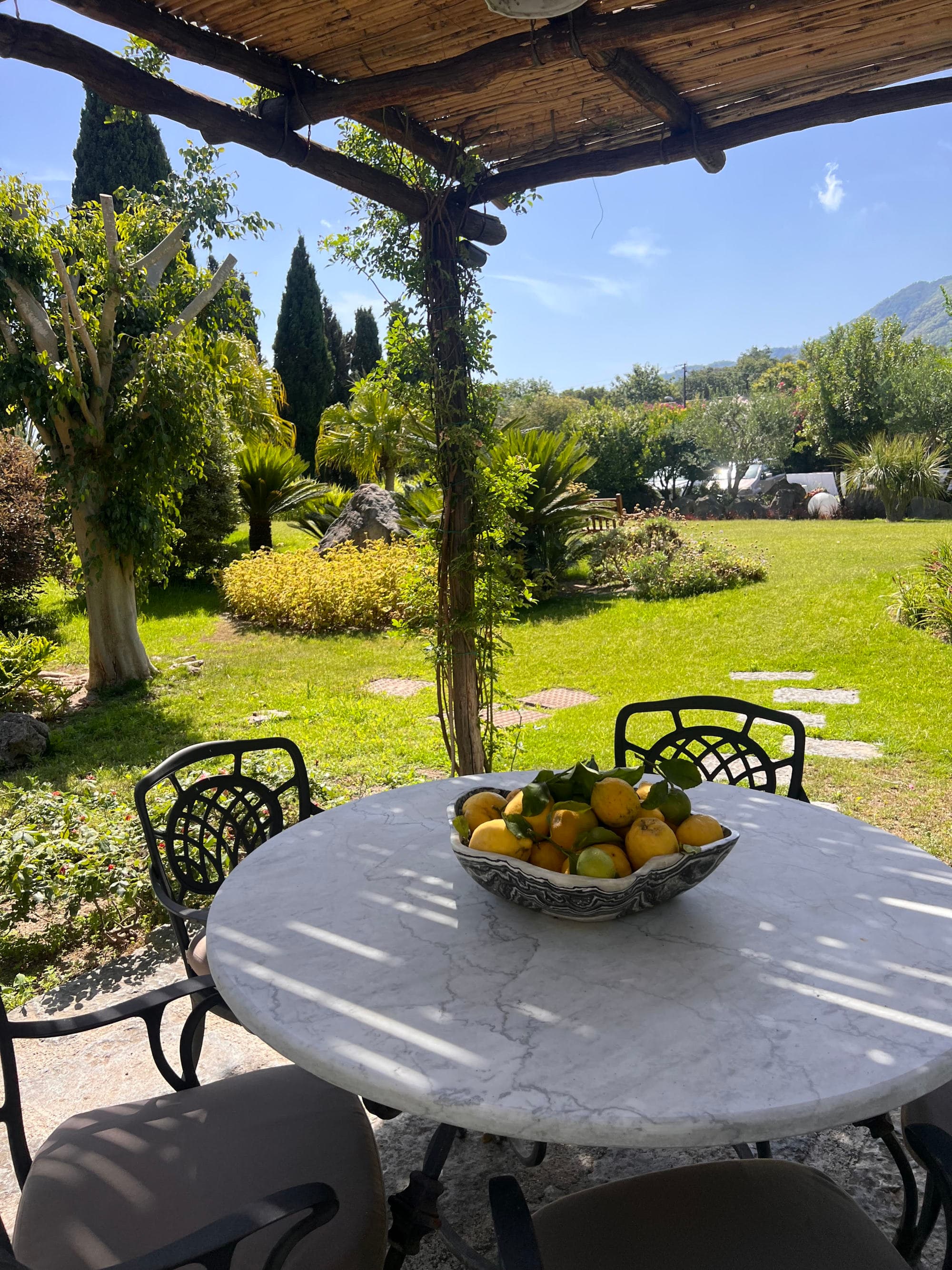 Outside dining with a a shaded overhang and green field in the distance on a sunny day.