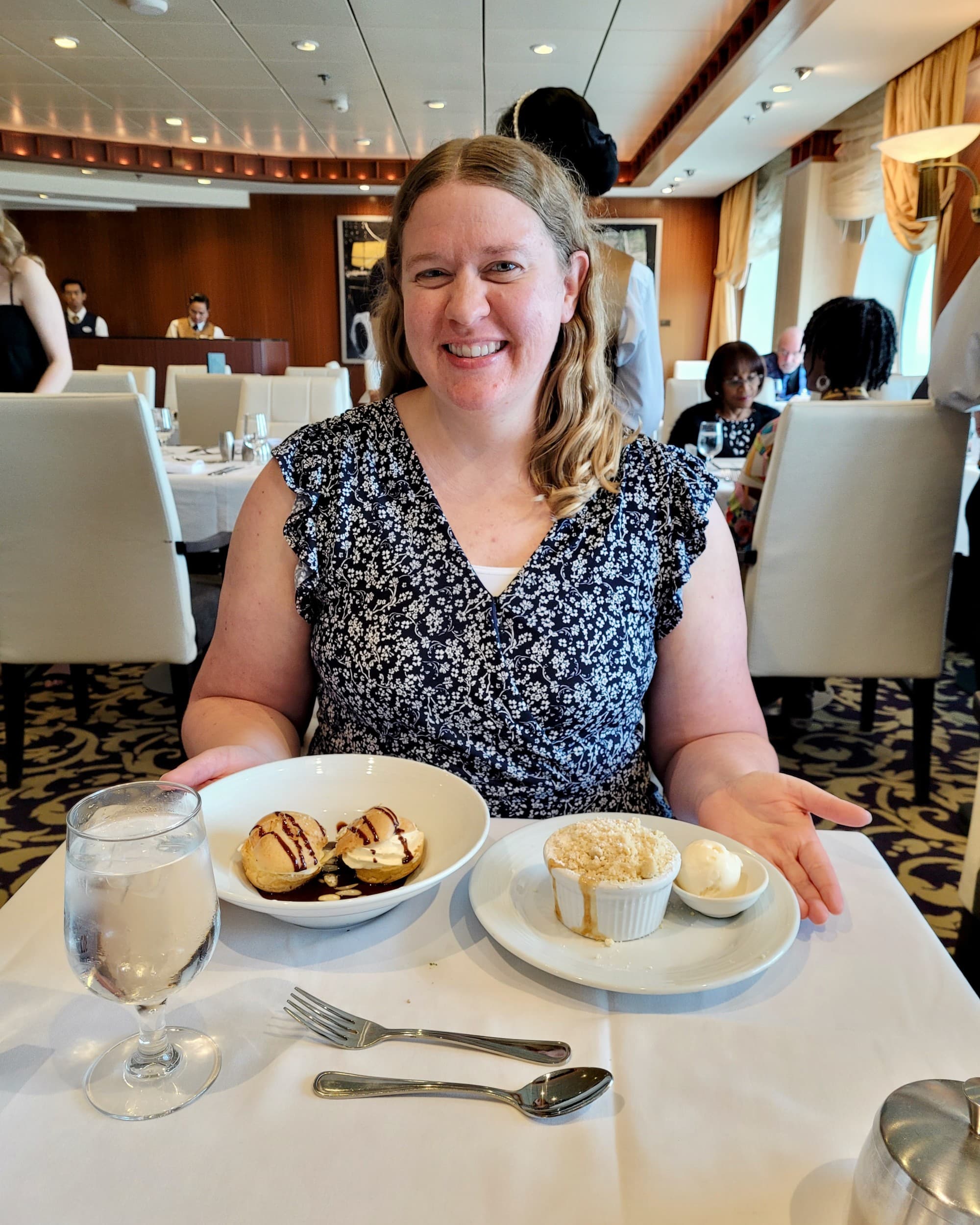 Travel advisor Stephanie sitting at a table with white tablecloth with two plates of dessert.