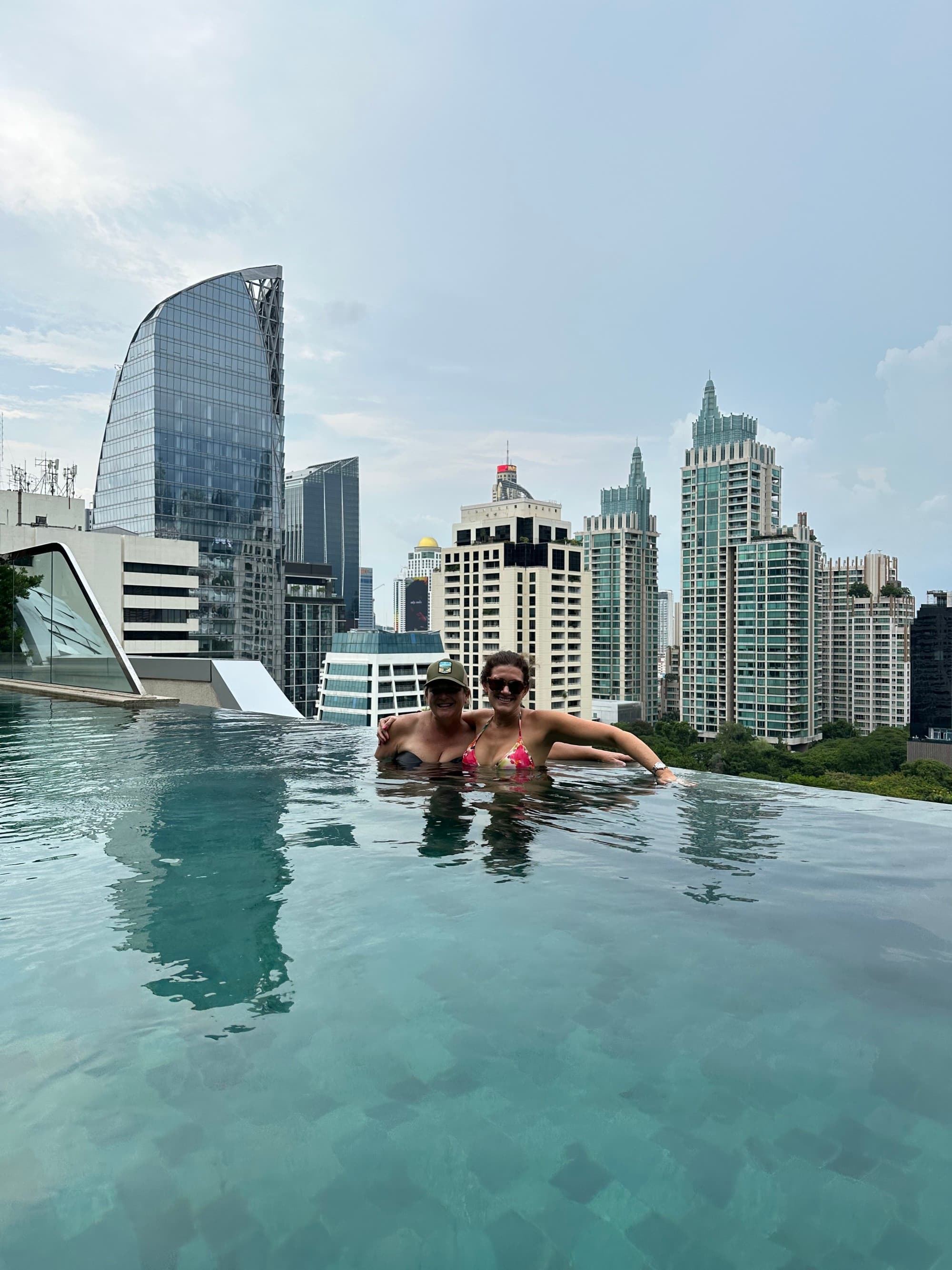 Travel advisor posing in a pool surrounded by sky scraper buildings.