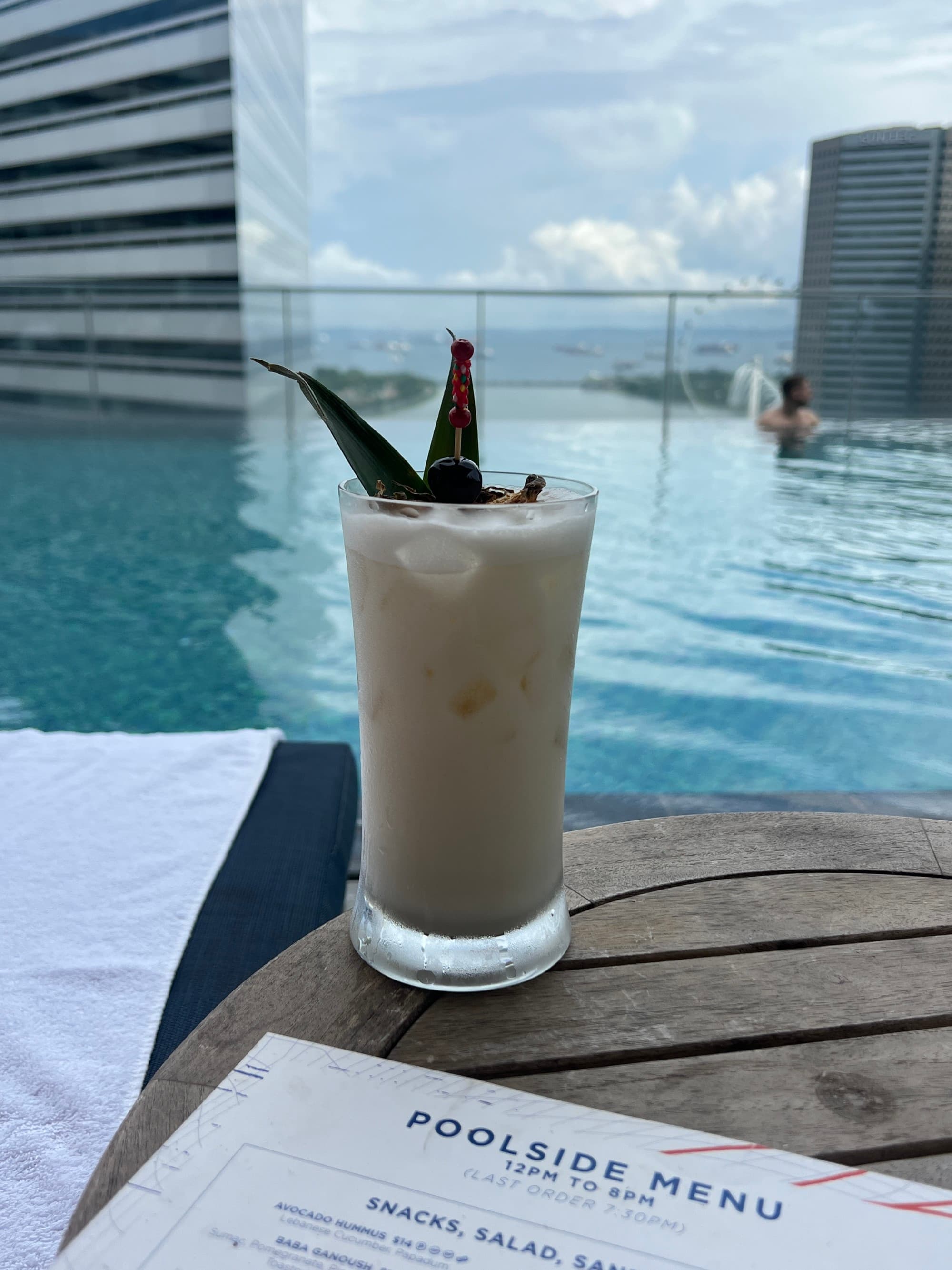 Cocktail on a wooden table next to a pool.