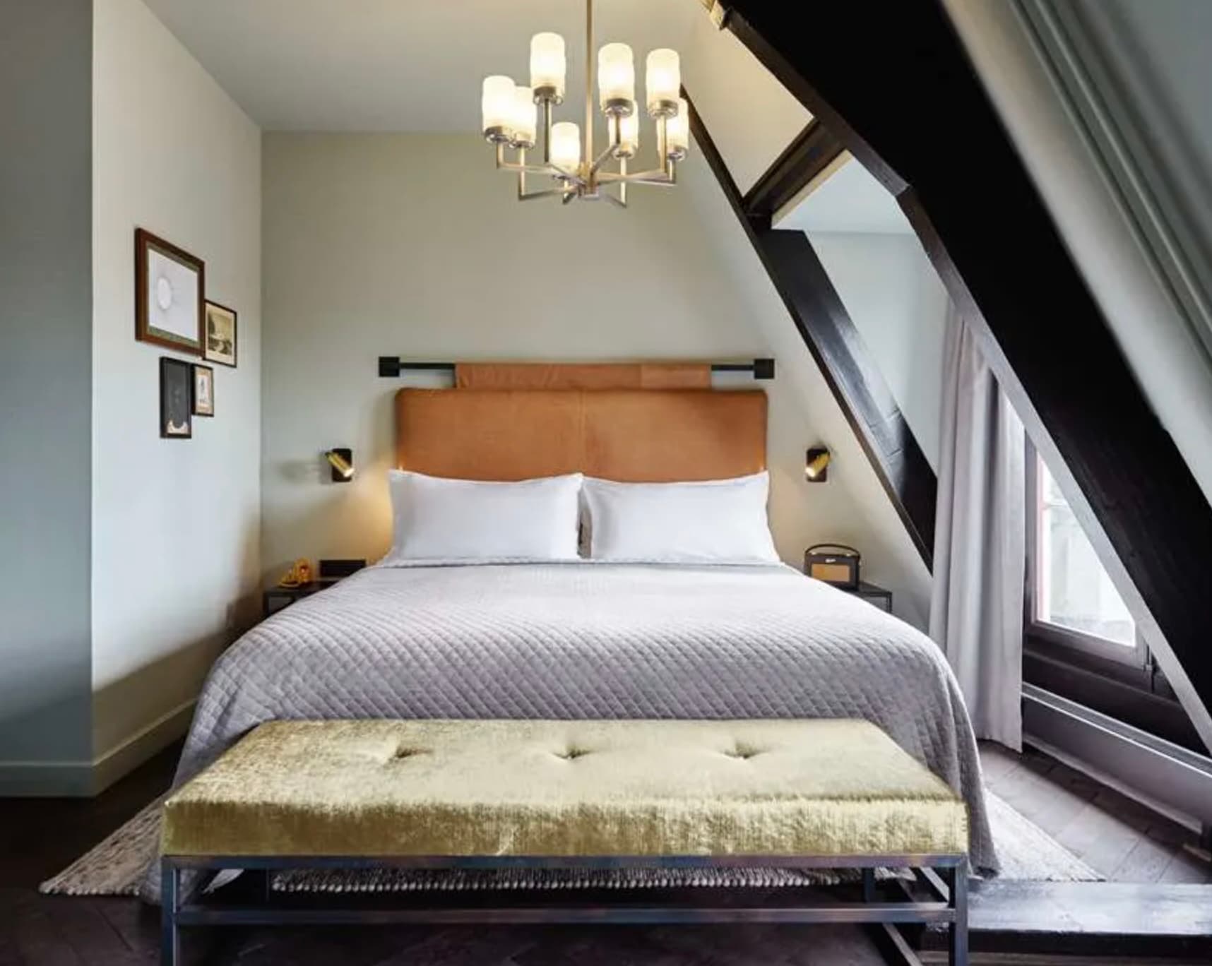 bedroom with a slanted roof, window and a cushioned bench