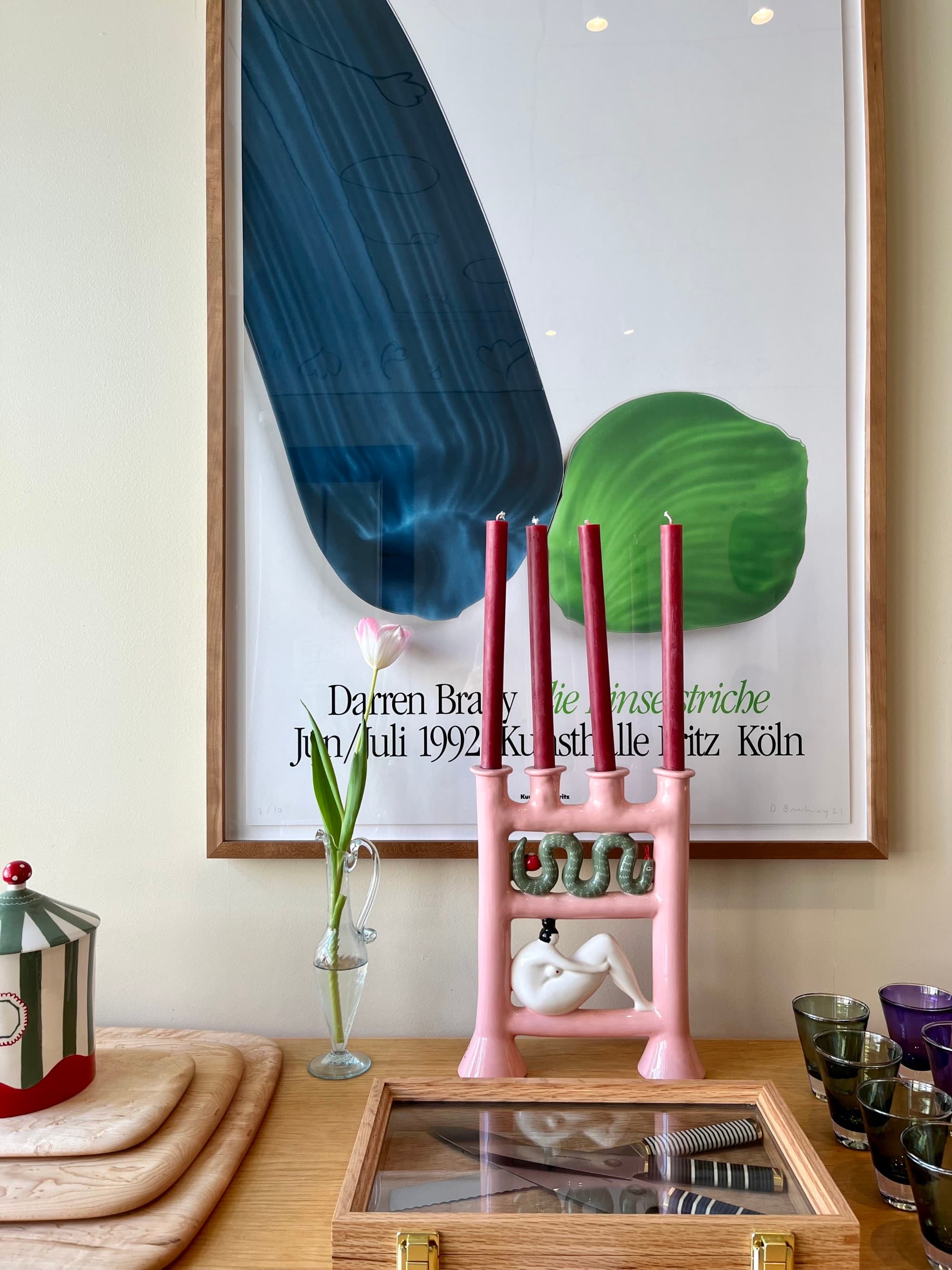 a funky pink candleholder in front of a large painting