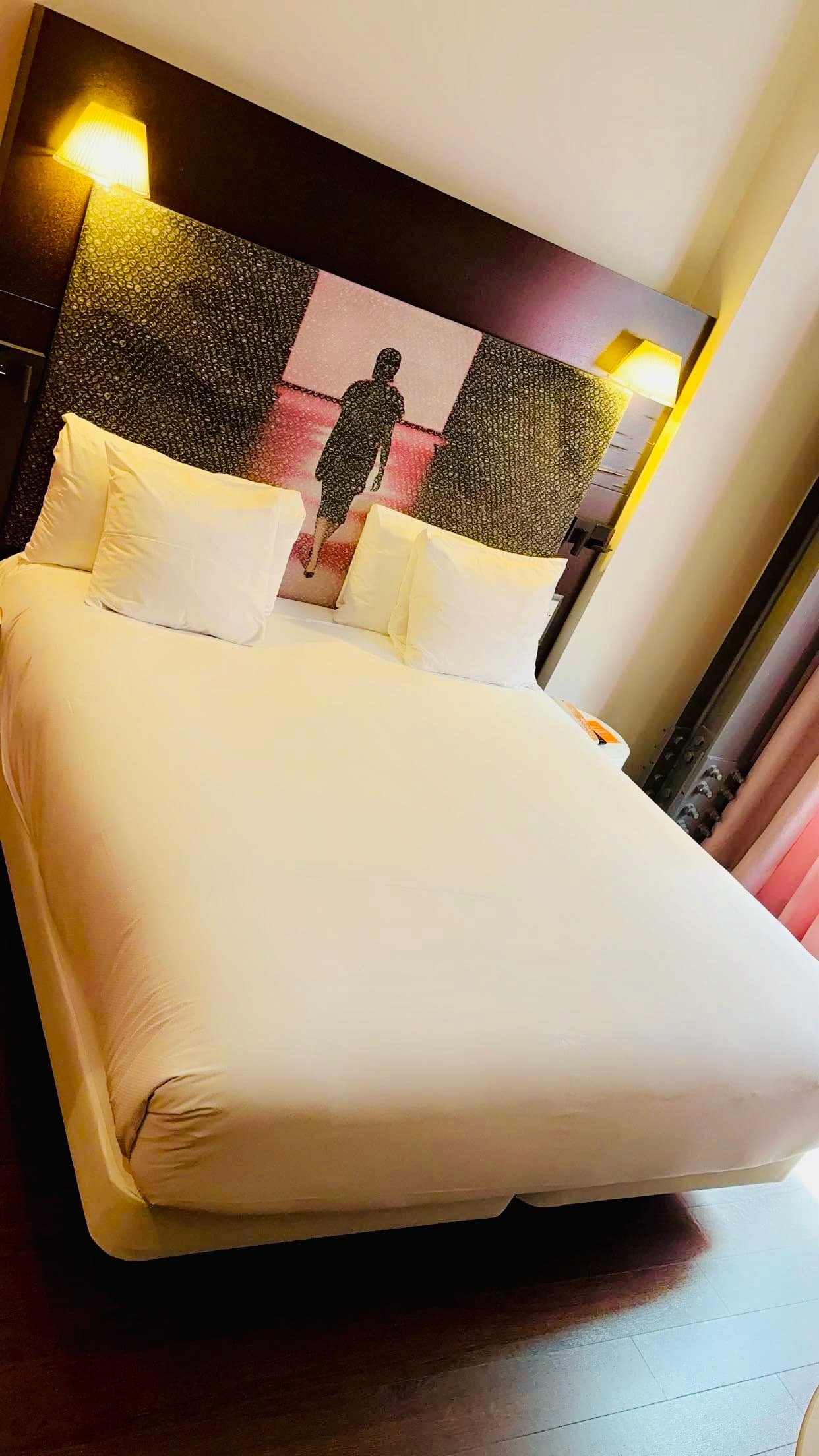 Hotel room with a queen-size bed with white linens.