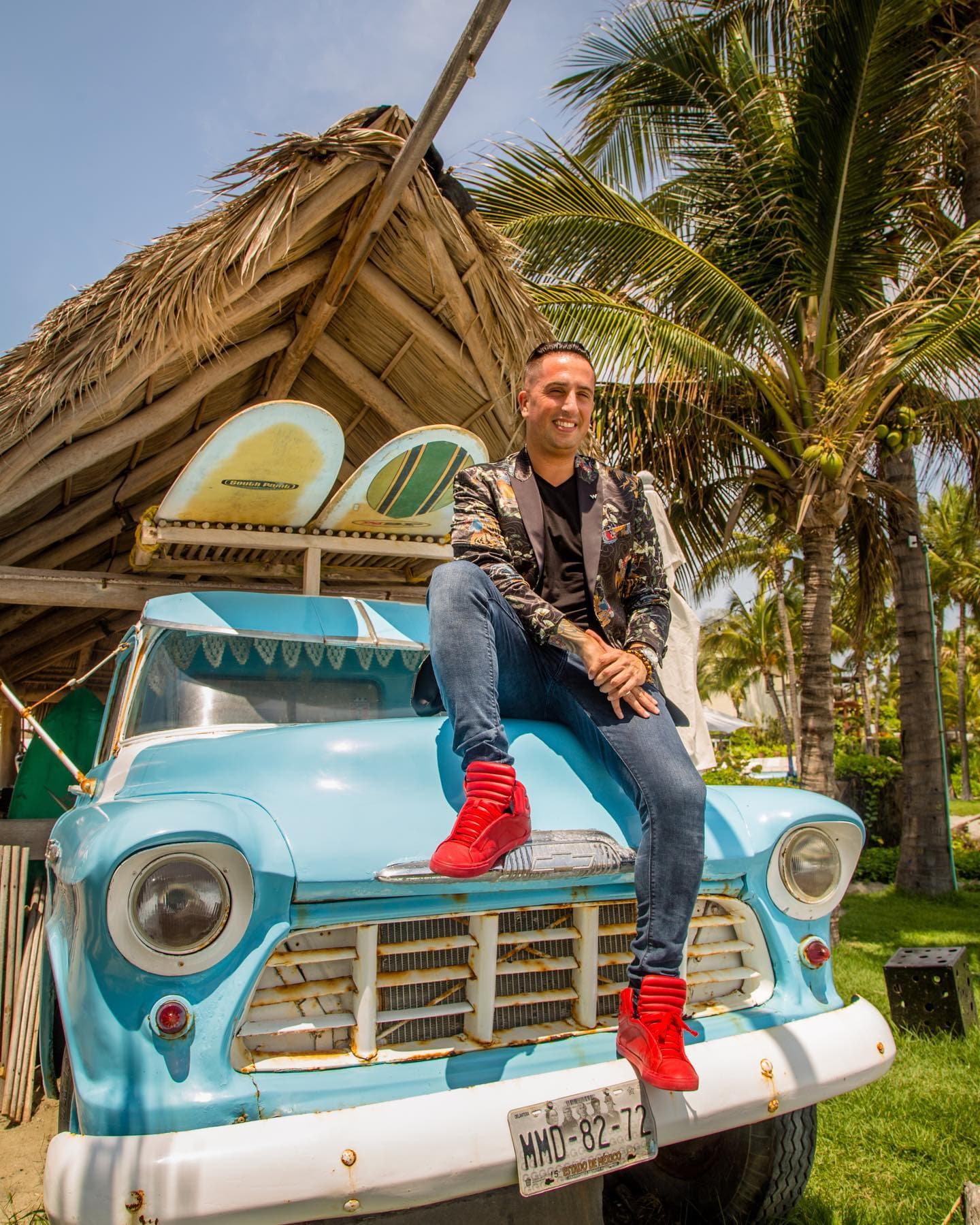 man with red sneakers sitting on an old light blue truck