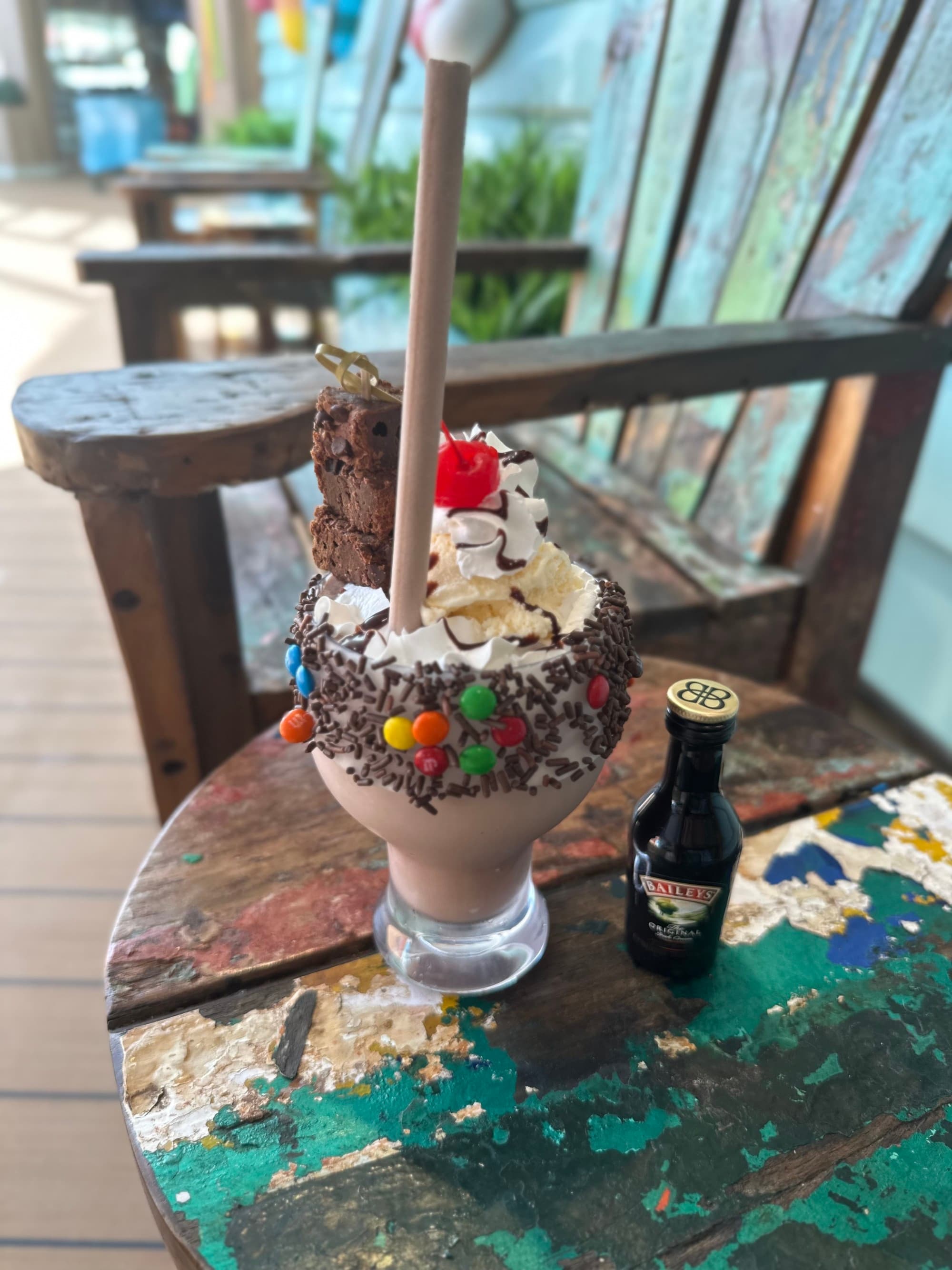 A milkshake from Desserted Dessert Bar sitting on a wooden table top in the shade.