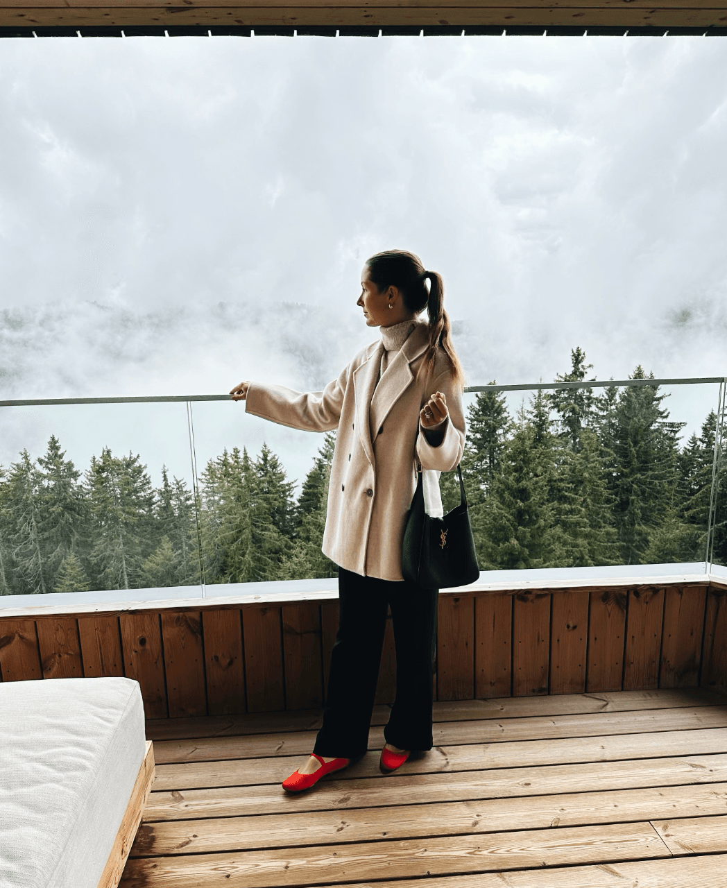 Travel advisor posing on a patio overlooking the trees on a cloudy day.