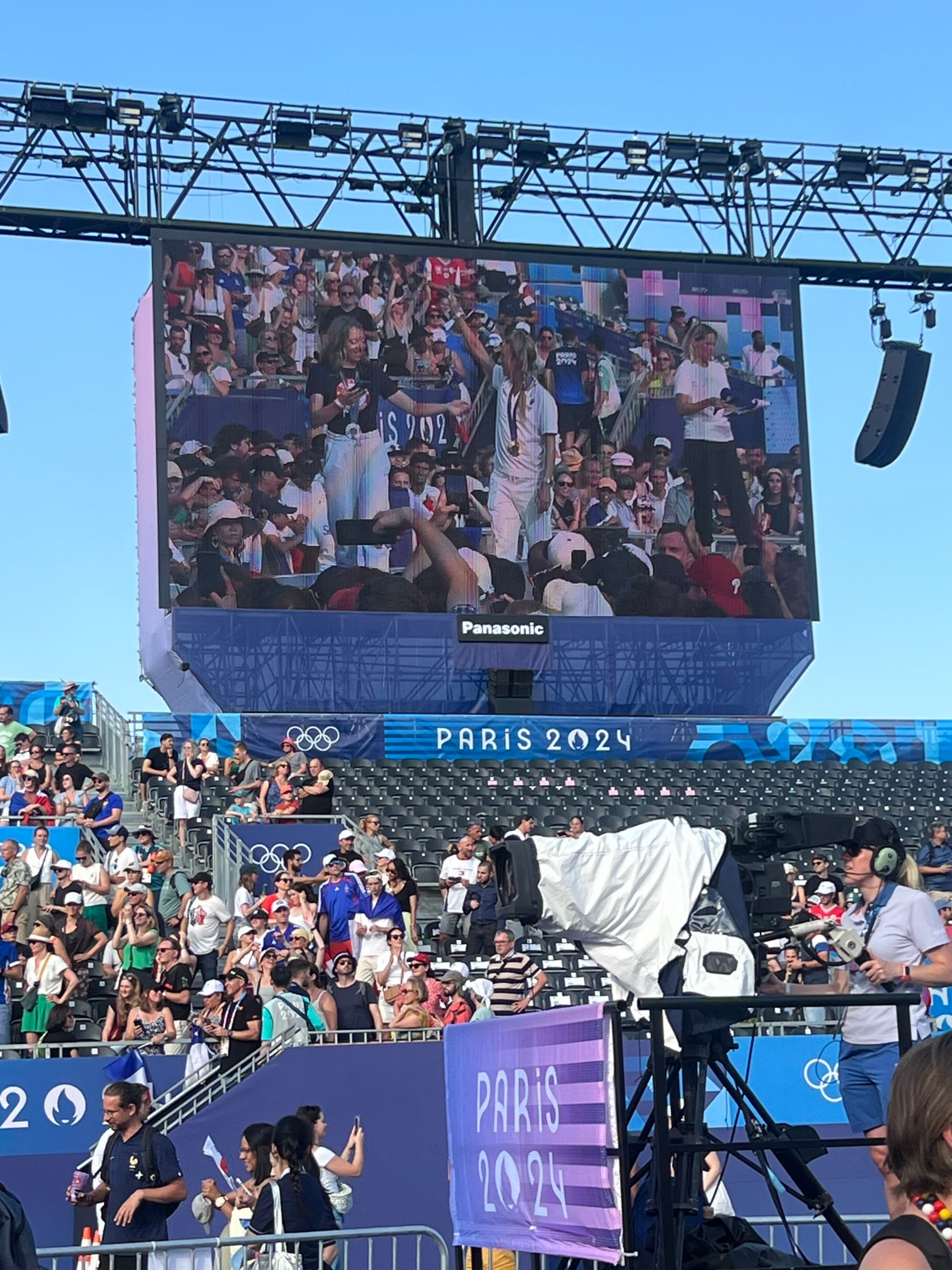 A screen above a stadium of people with a zoomed-in view of other audience members