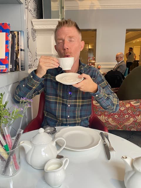 Advisor holding up a tea cup and plate and posing for a photo
