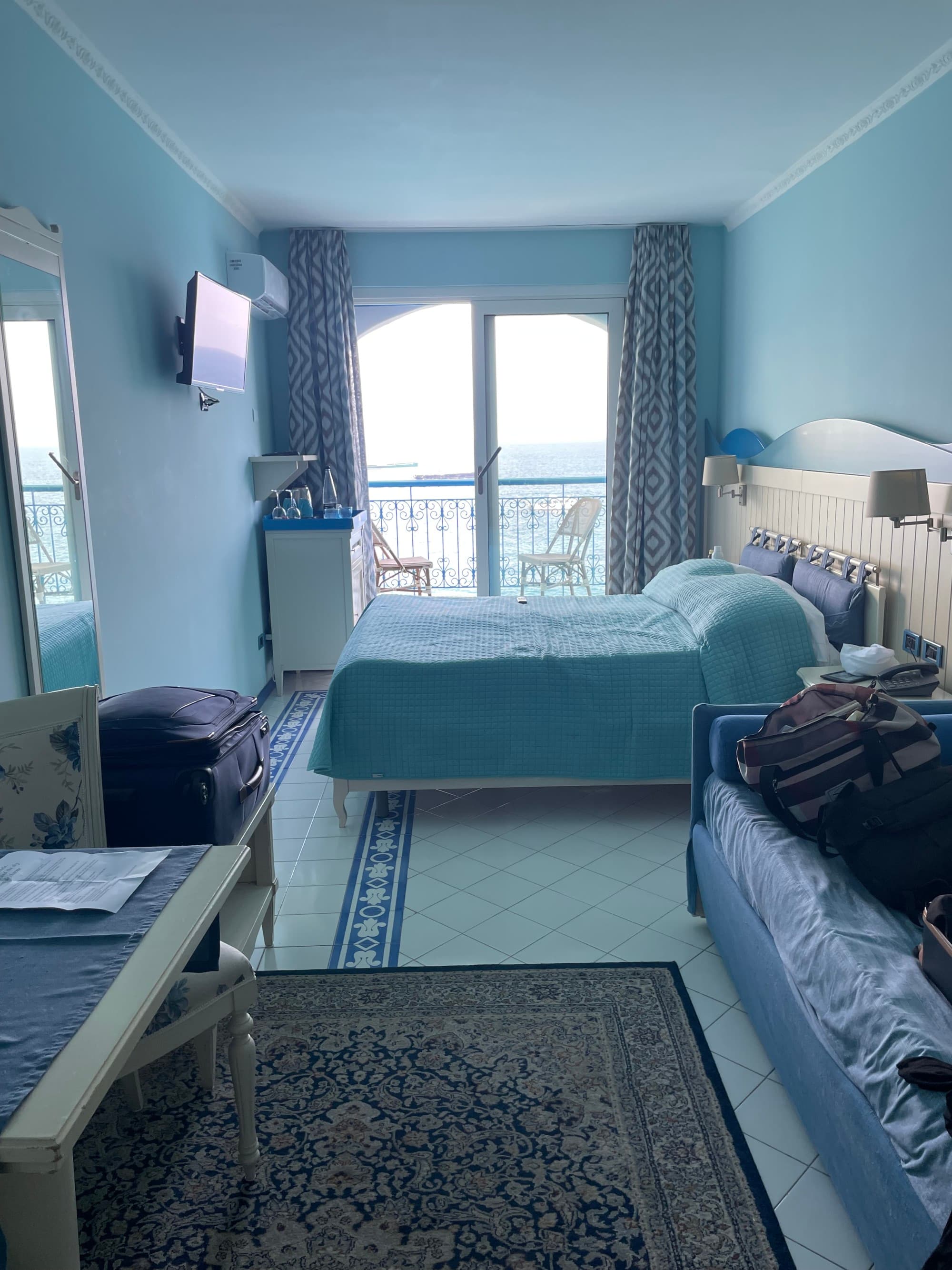 A hotel room suite with a bed against a four-panel window