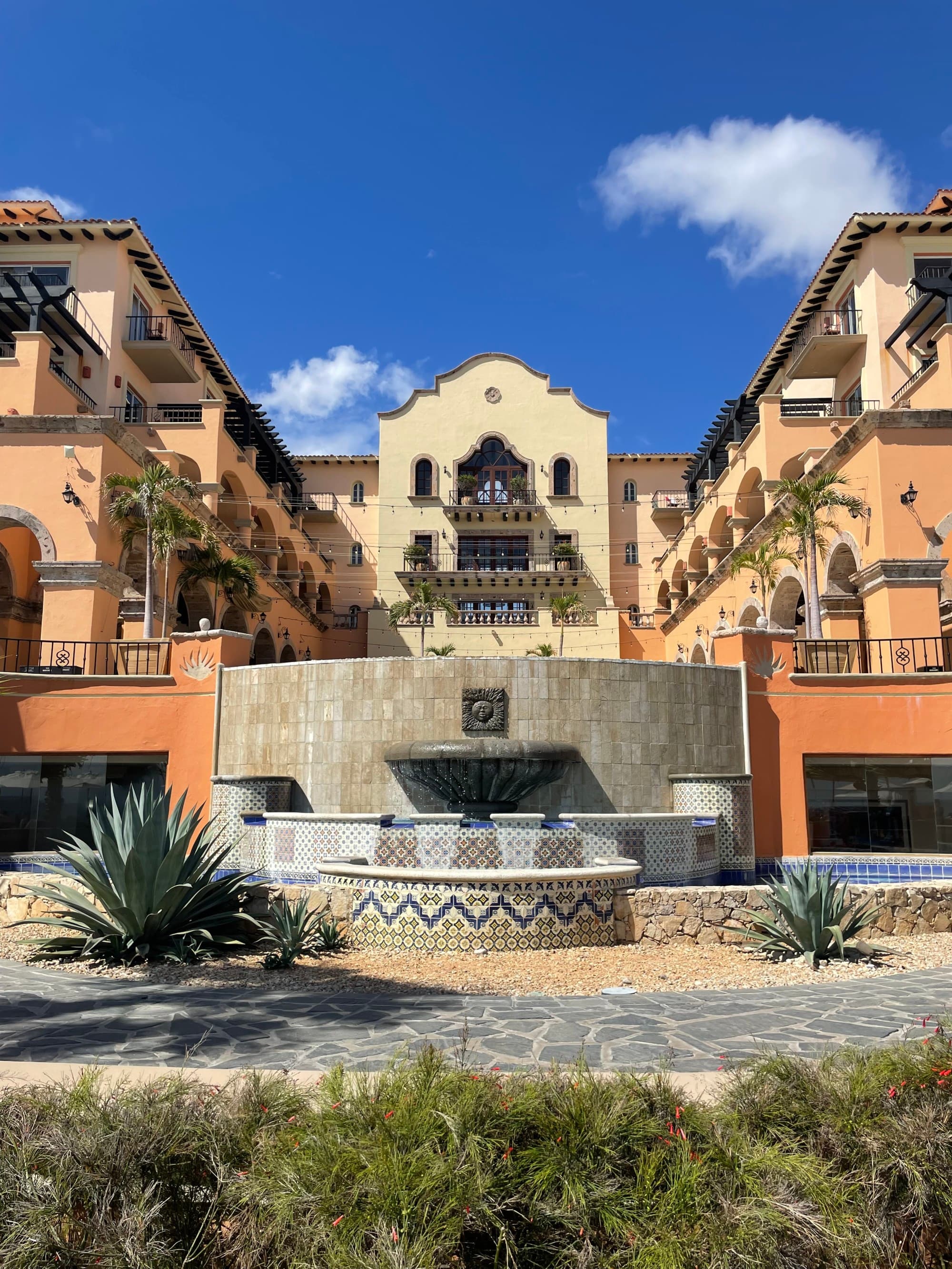 An orange and beige building with a water fountain in the front