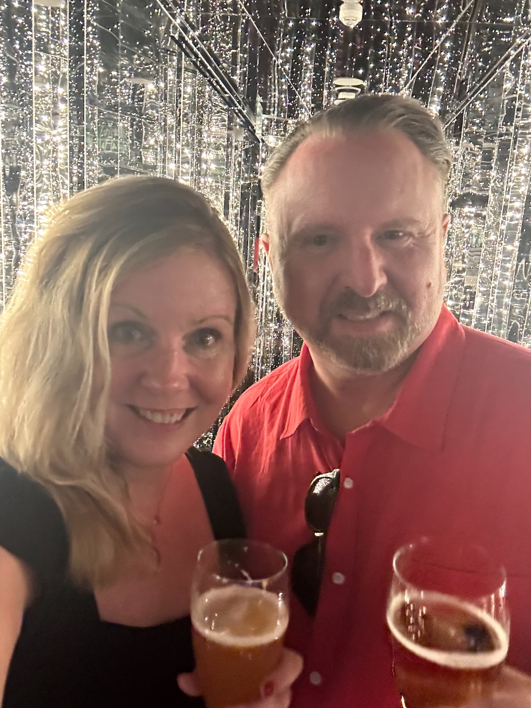 A couple posing for a selfie photo while holding drinks