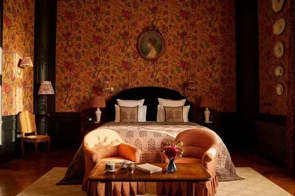 an old-fashioned bedroom with floral wallpaper and a cozy bed
