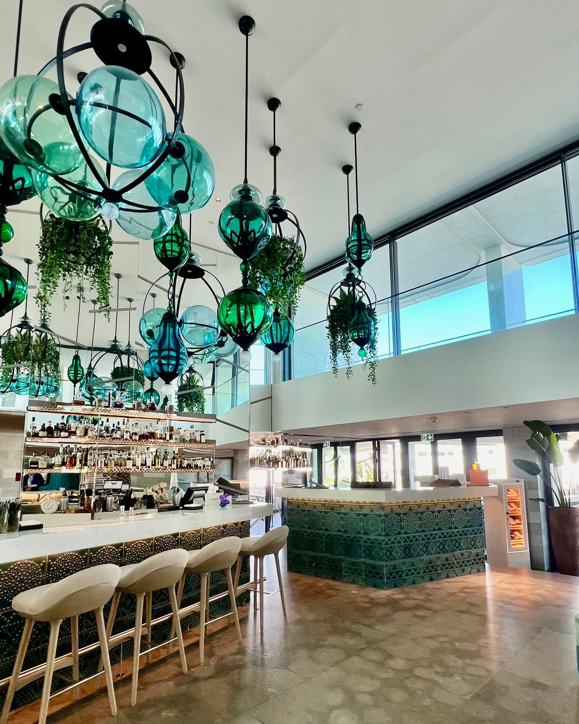 A hotel lobby with multiple green and blue glass lights hanging from the ceiling