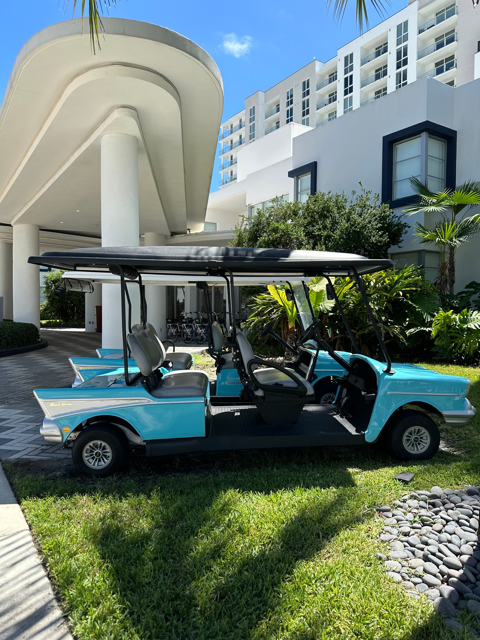 A blue golf cart in front a white hotel building