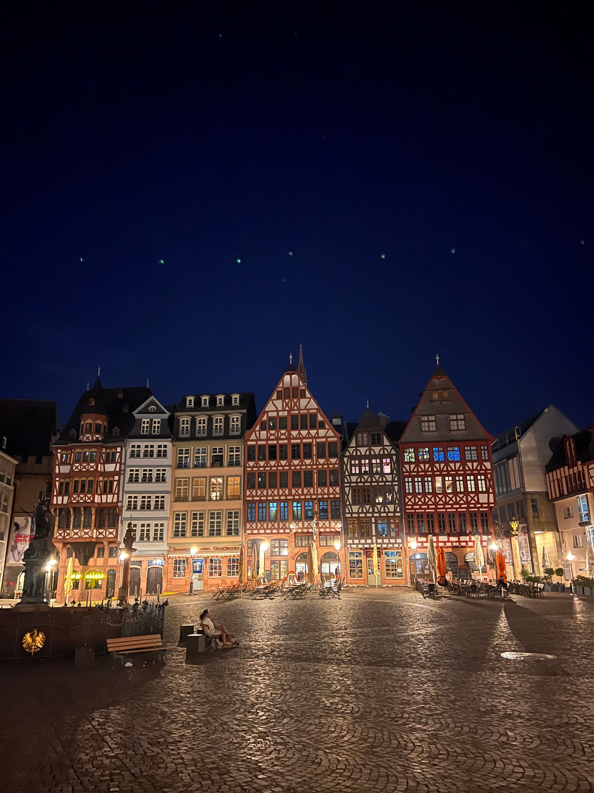 A body of water in front of colorful buildings lit up at night