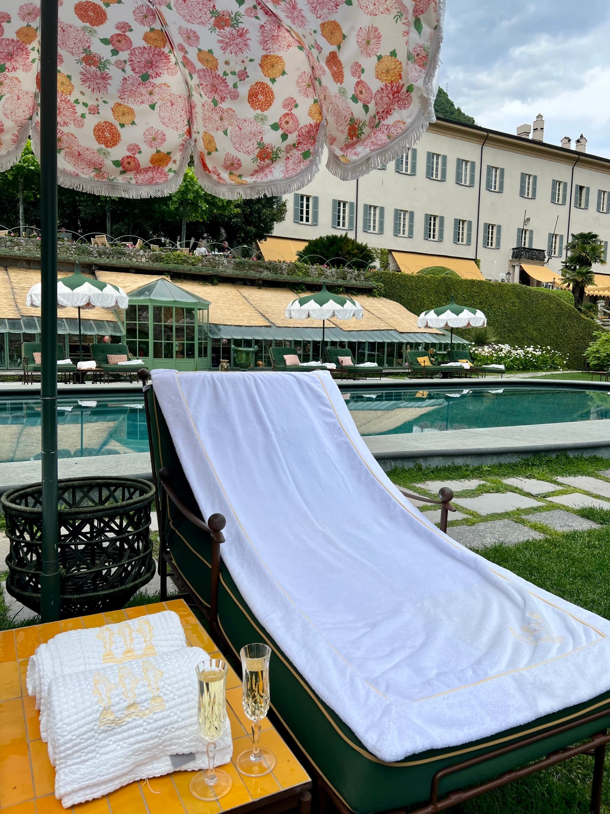A lounger by the lake under an umbrella on a sunny day.
