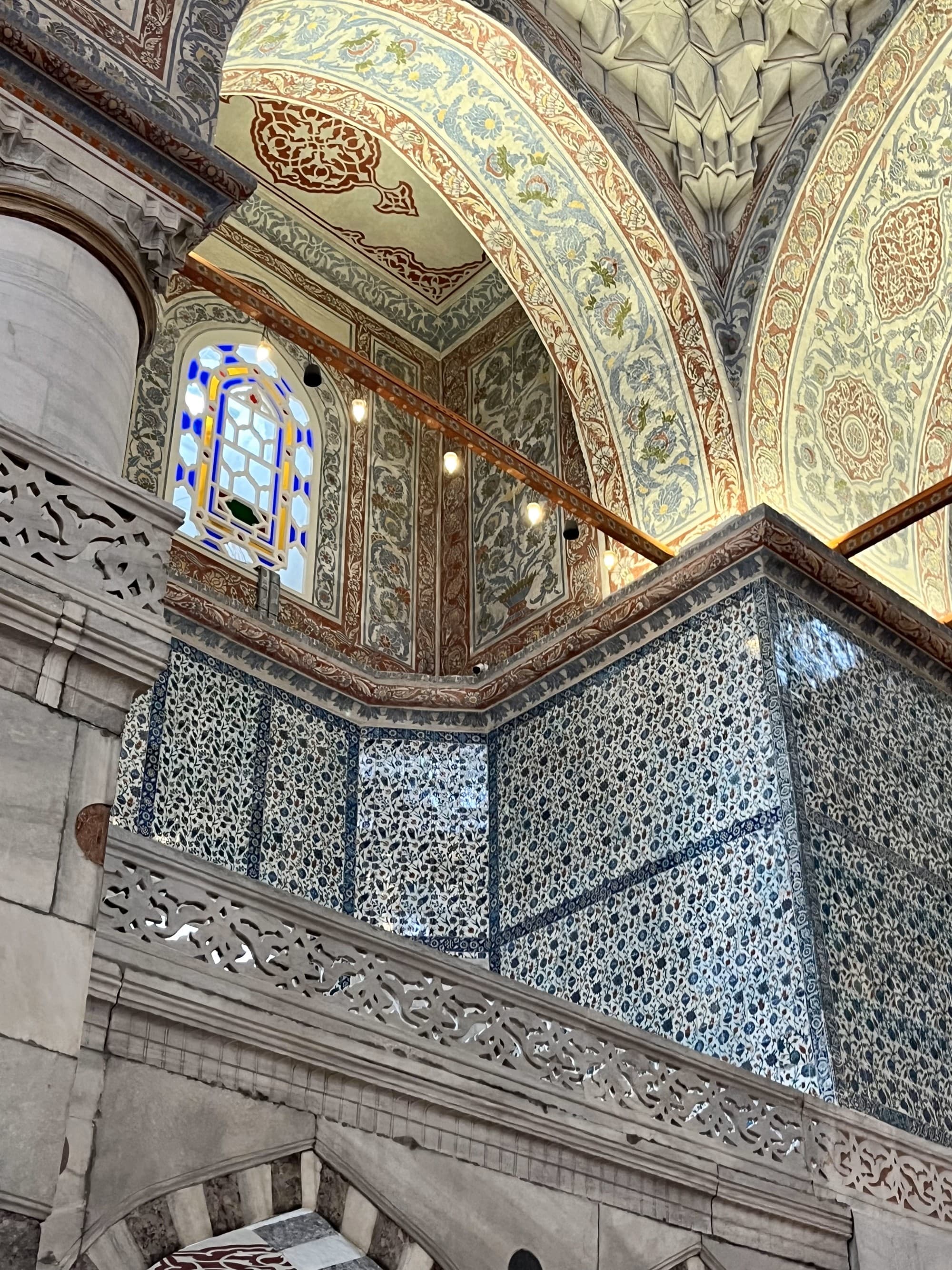 Intricate interior of the Blue Mosque with painted tiles and engravings and arched ceilings.