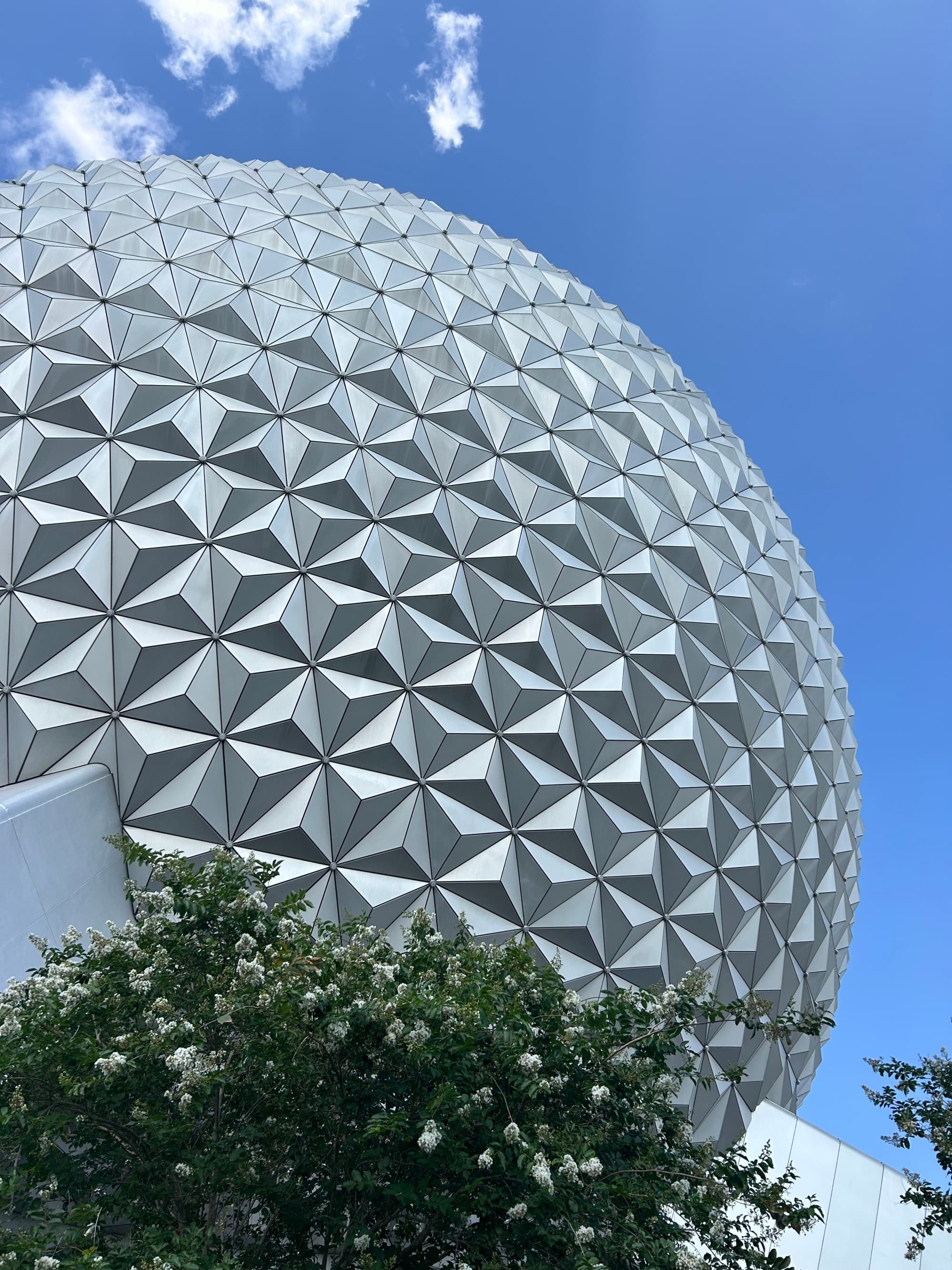 The EPCOT Center stands tall against a clear sky doted with clouds.