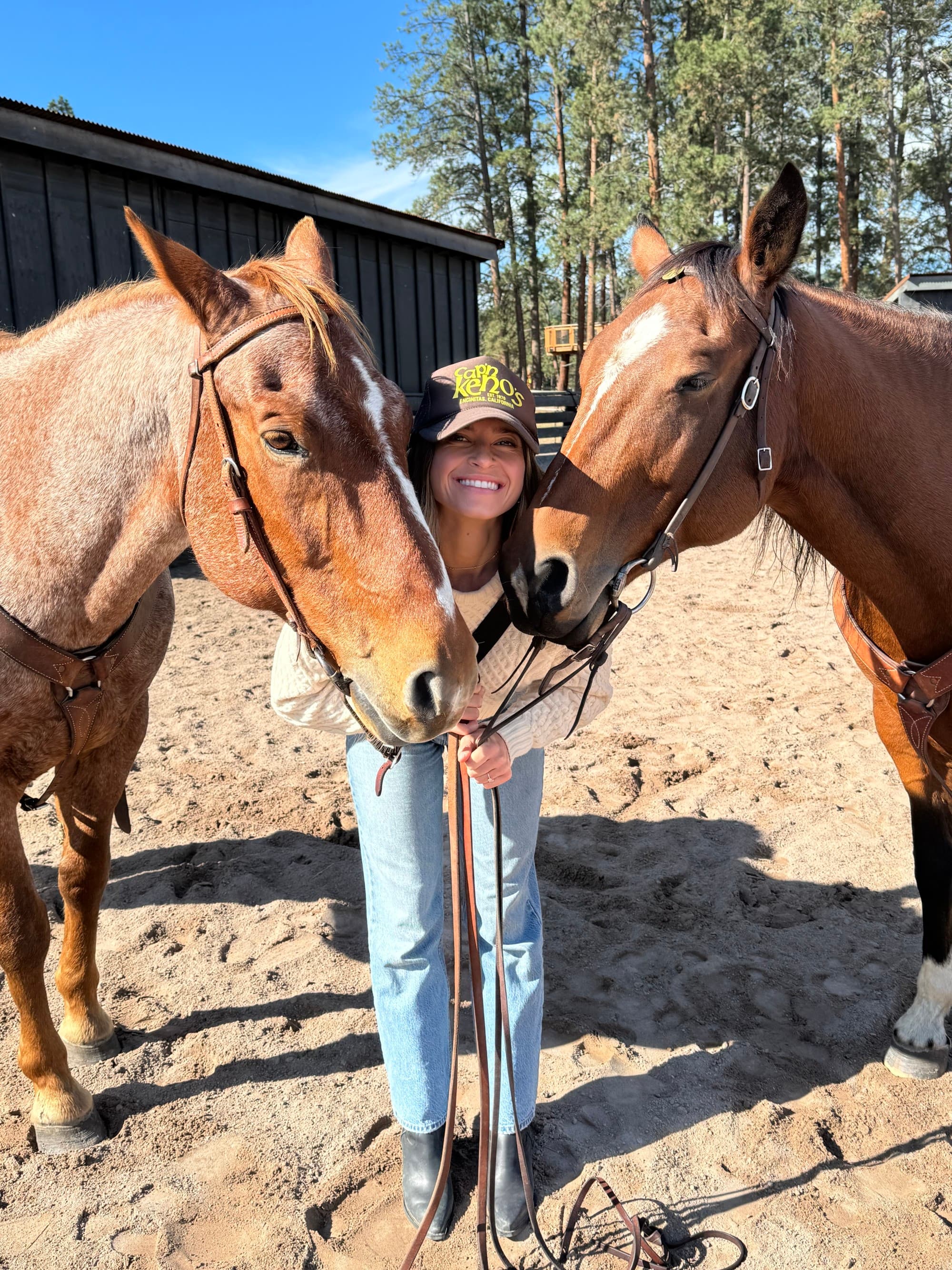 A woman poses with two horses.