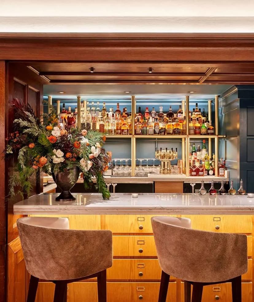 two bar stools at a bar counter with shelves of liquor in the background