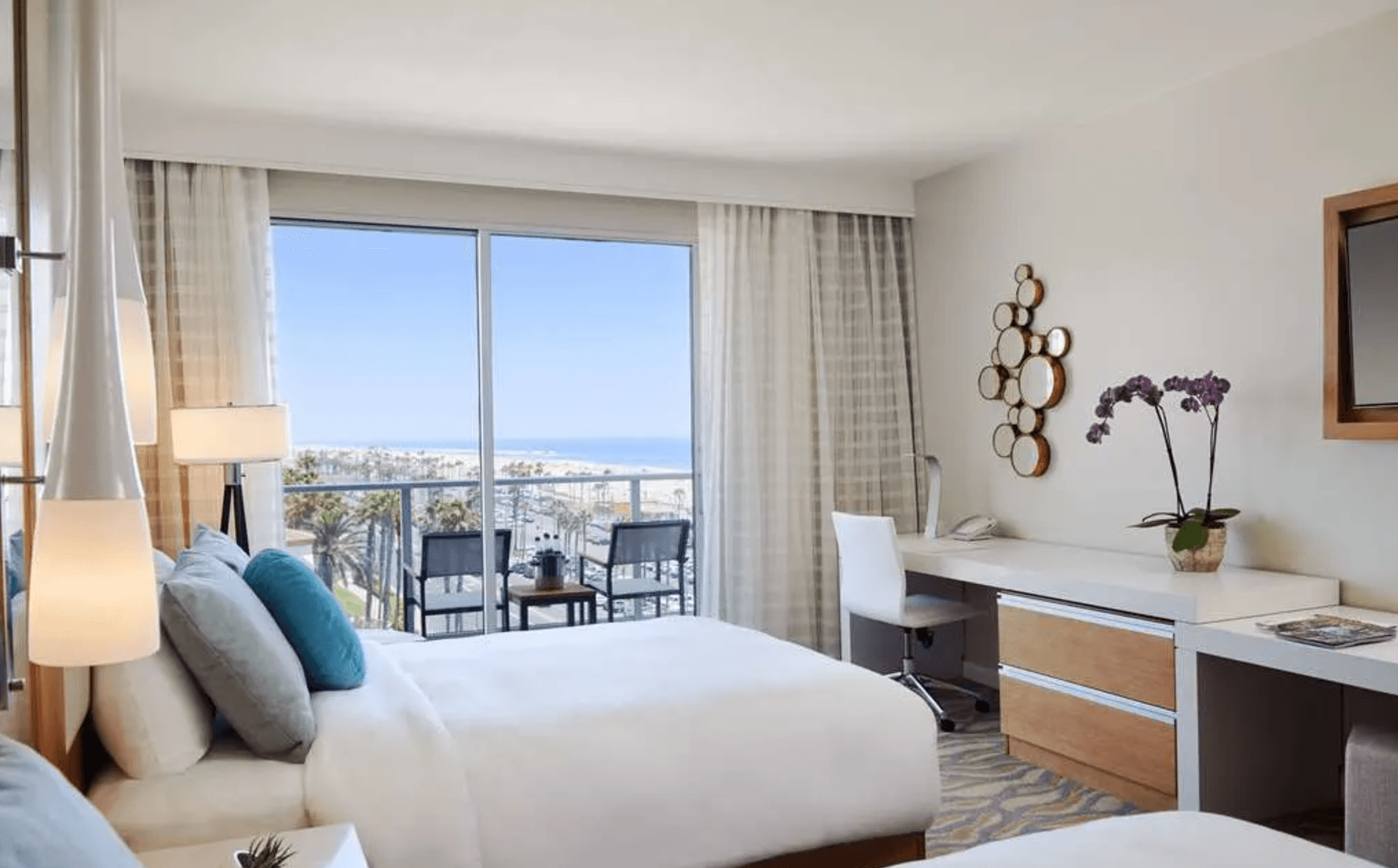 Interior of a hotel room at Paséa Hotel & Spa with white and neutral furnishings and a balcony with beach views.