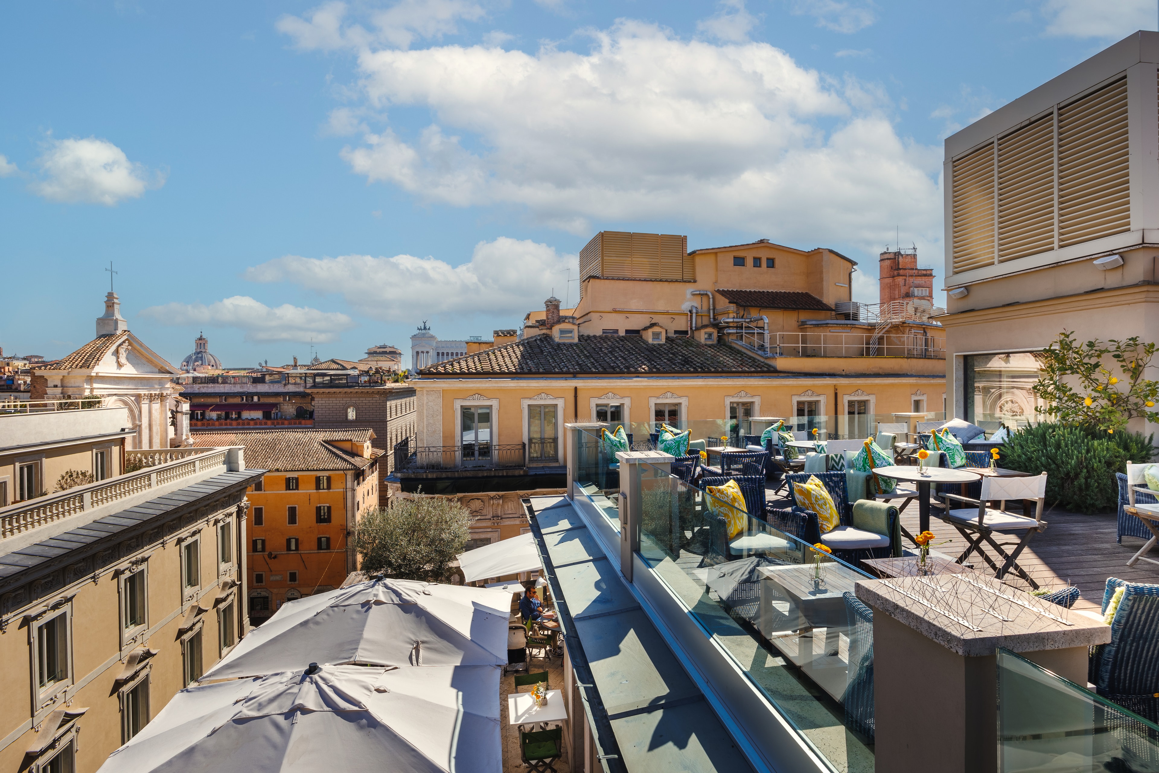A picture of the rooftop at the Singer Palace Hotel in Rome with outdoor seating, overlooking other buildings.