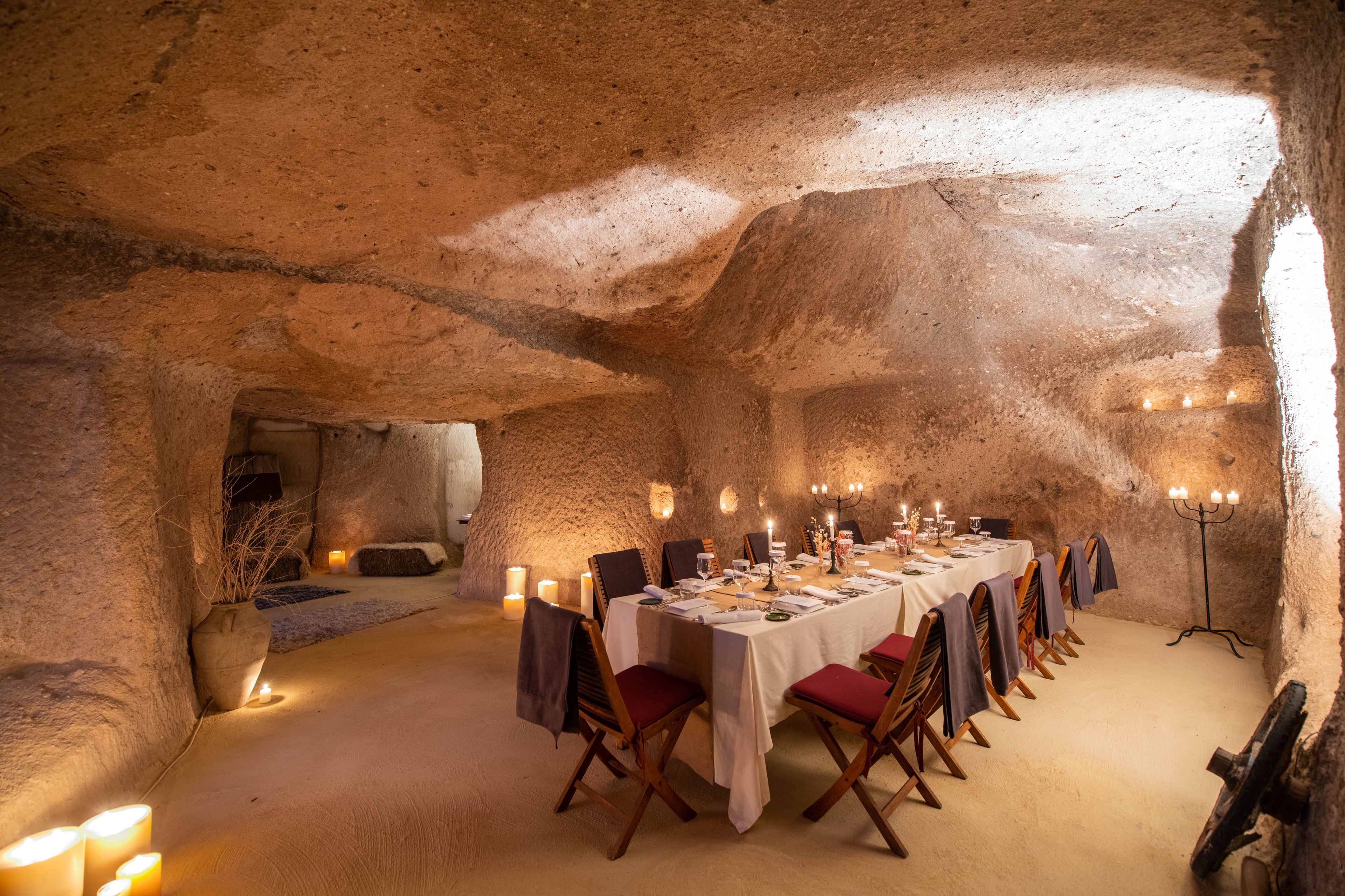 A view of a cave with an private dining setup with warm lighting and candles.
