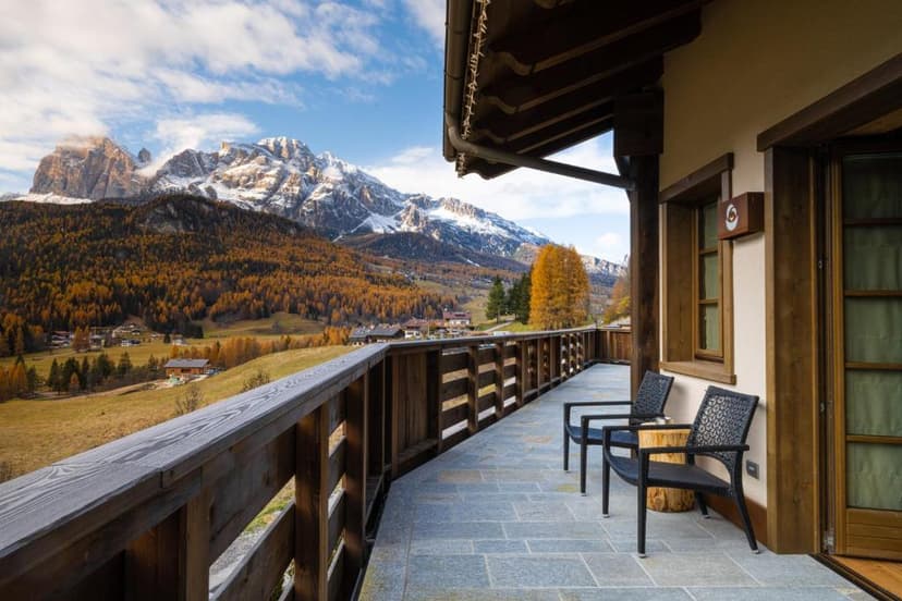 A view from a balcony of snow-capped mountains and lush greenery.