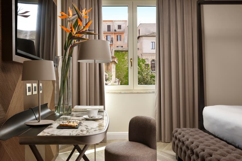 Hotel room at Grand Hotel Palatino showing a desk, tv and the end of a bed, with a city view.