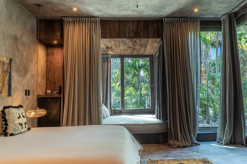 hotel room with a large white bed and a smaller day bed near a draped window