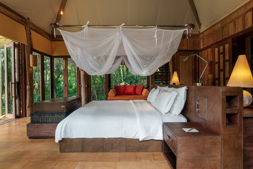 a white bed with a white net hanging over it in an open-air luxury villa