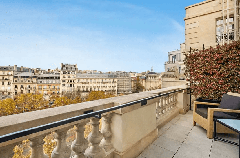 A stone balcony at the Shangri-La Paris with a lounge chair, overlooking the city.