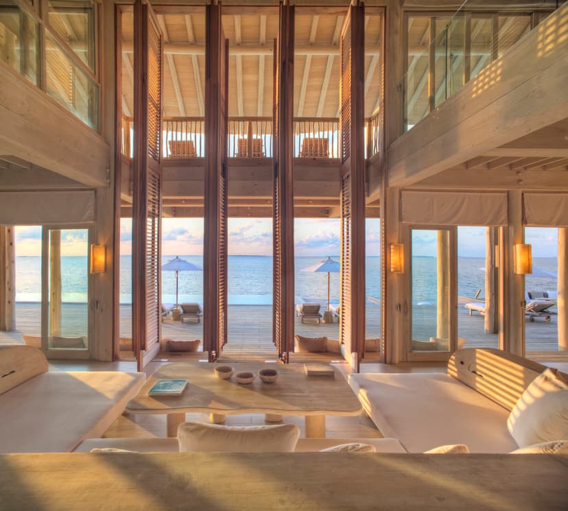 a living room with floor-to-ceiling windows and wooden shutters overlooking the ocean
