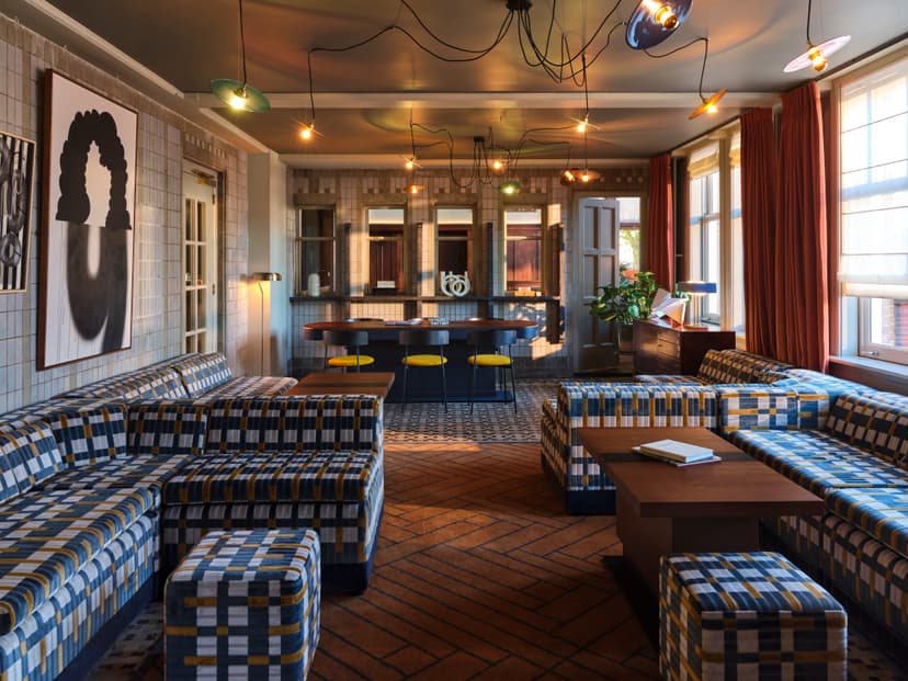 Hotel lobby with plaid couches, a bar with yellow chairs and abstract art on the wall