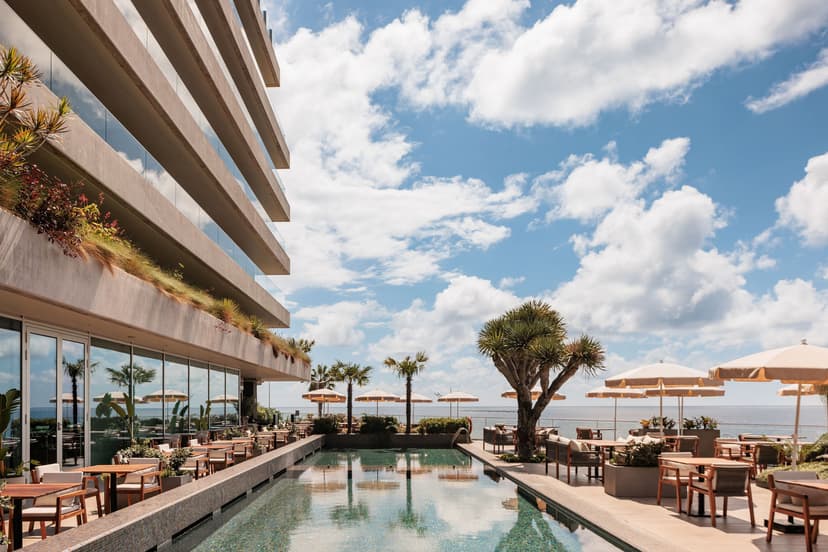 A view of a tranquil pool area at Saccharum Resort & Spa, with dining areas either side.