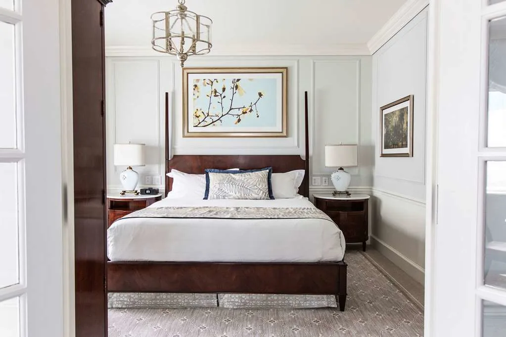 an elegant hotel room wit a bed in front of a nature painting