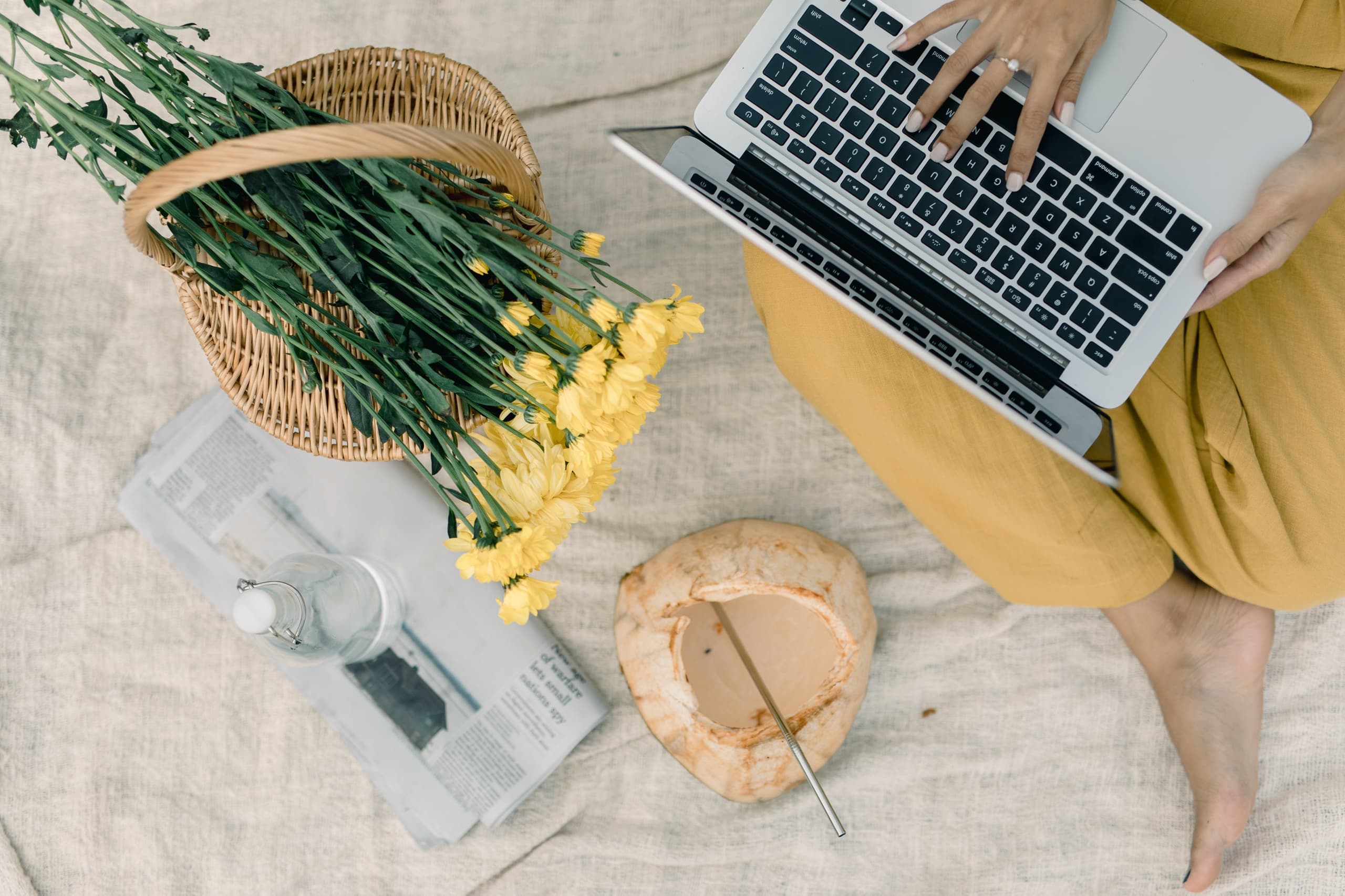 Woman using laptop next to yellow flowers in a photo taken from above
