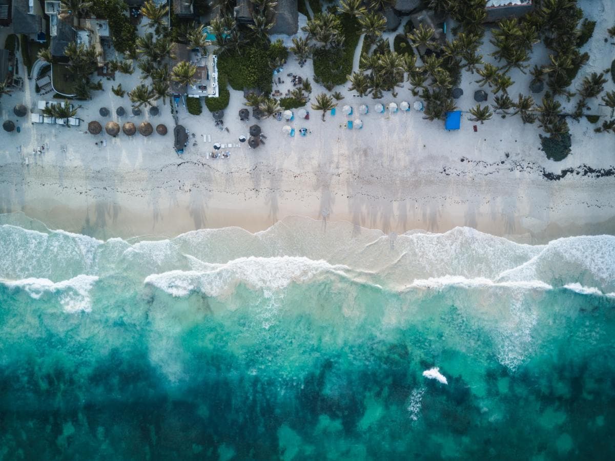 Birdseye view of clear blue ocean waters and white sands on a beachside resort in Tulum, Mexico in Central America.