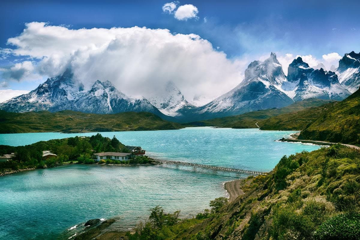 Fluffy white clouds over mountains with ice caps over blue lake in Torres del Paine National Park, Chile in South America.