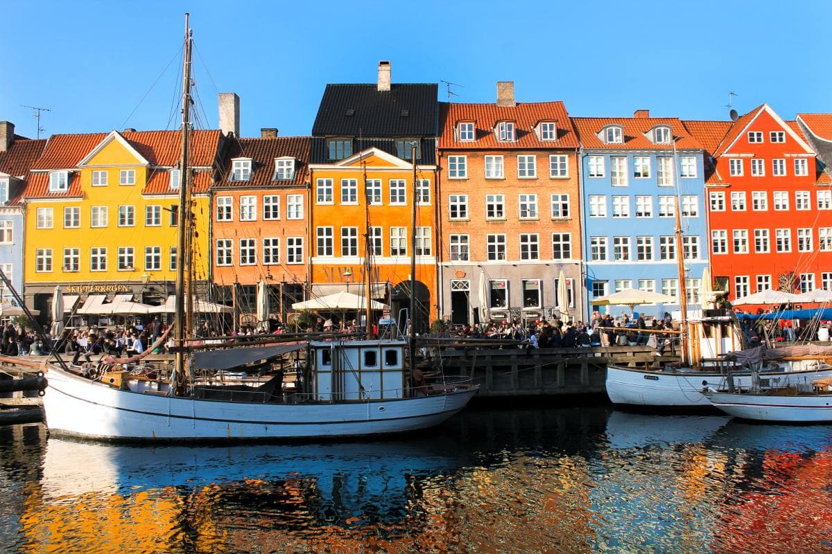 Sailboats in the water with colorful buildings in the background in Denmark