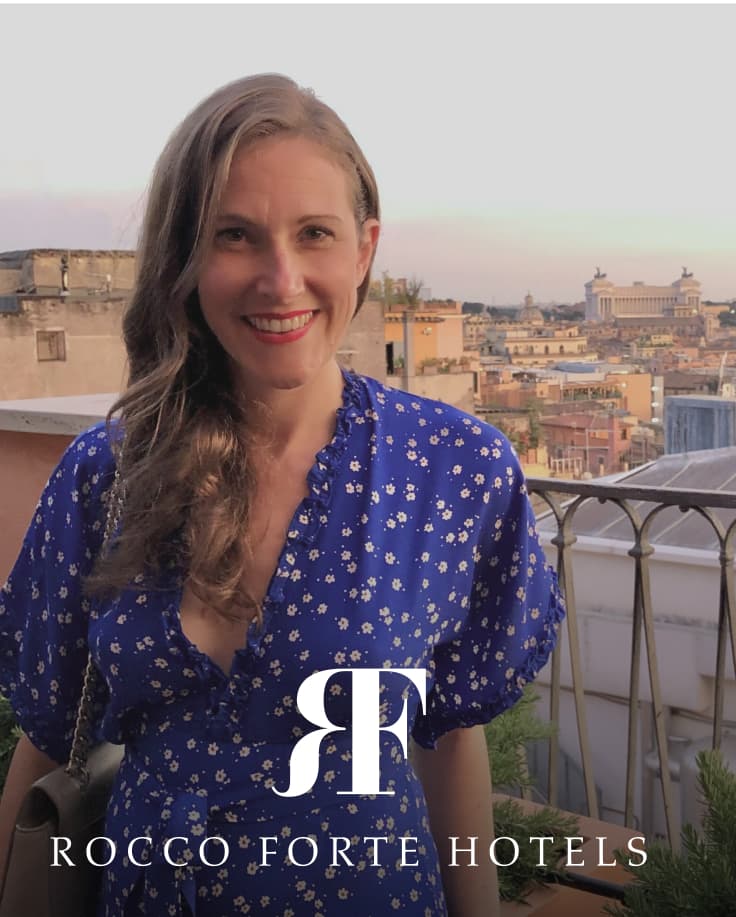 woman in a blue dress stands on a balcony