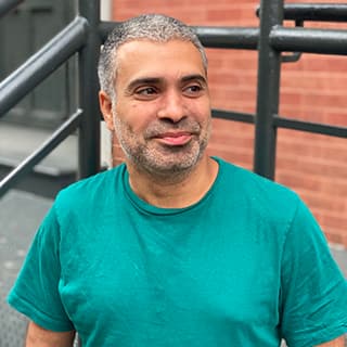 Man wearing a turquoise shirt and smiling