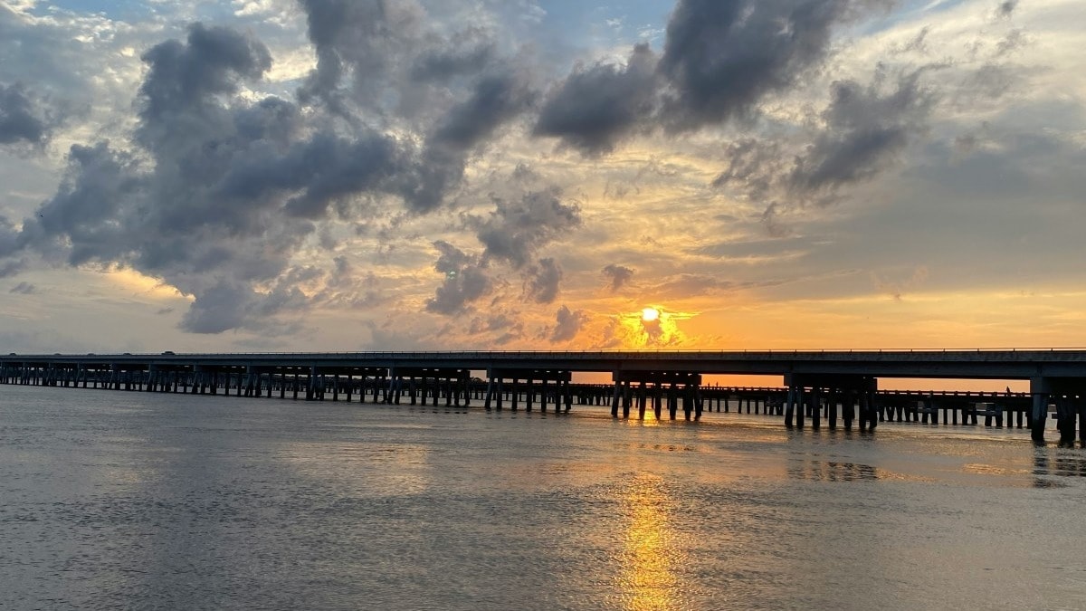 Beach pier over a body of water at sunset