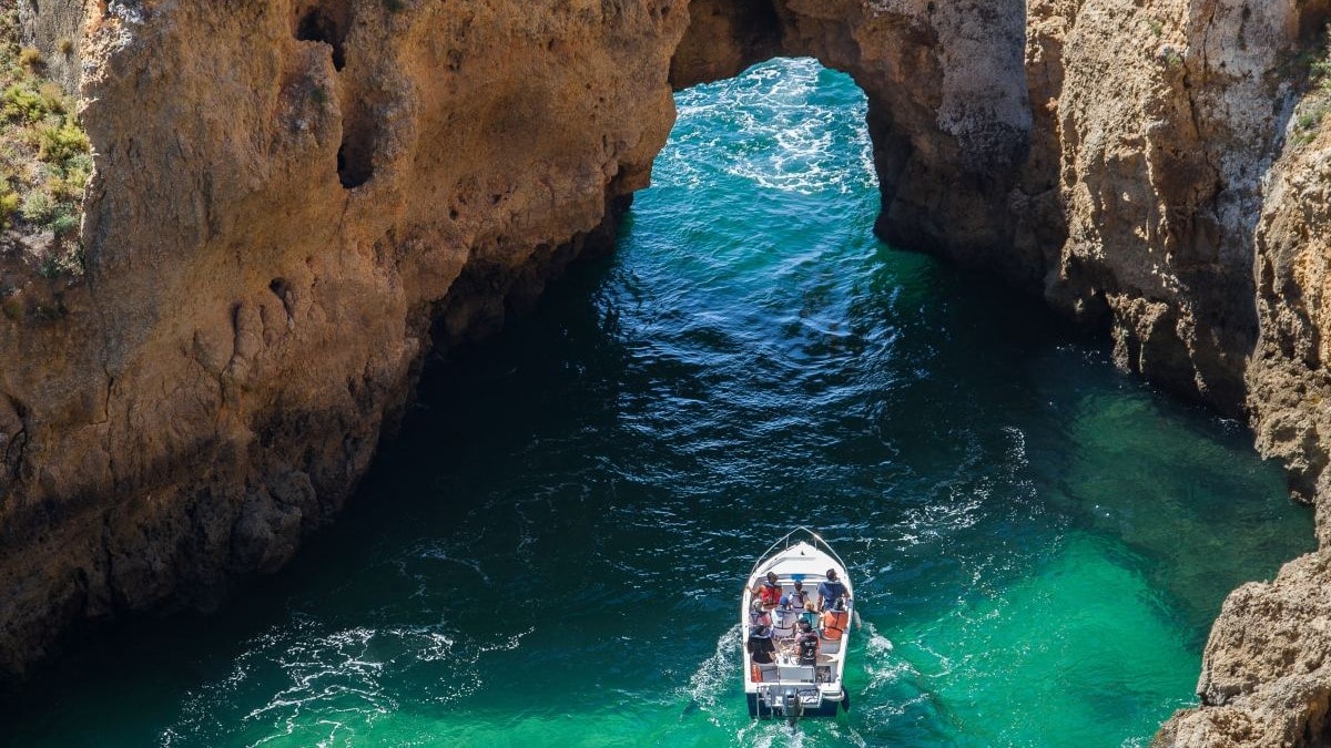 two boats in the sea going under rock formations