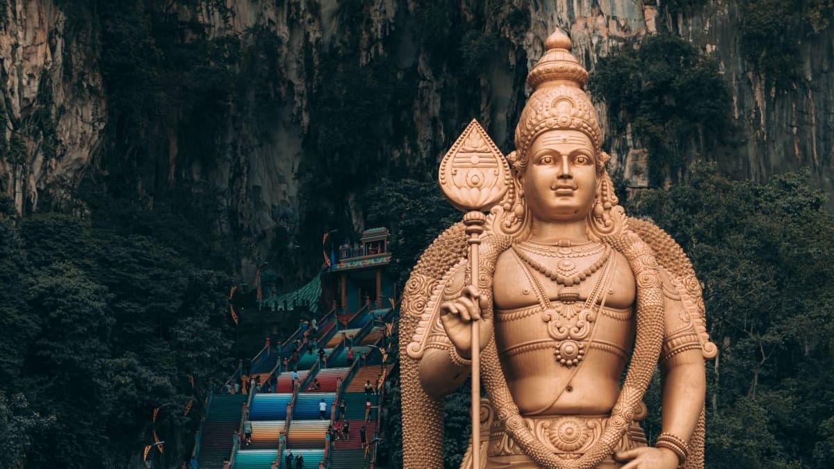 Large gold statue in front of a cave.