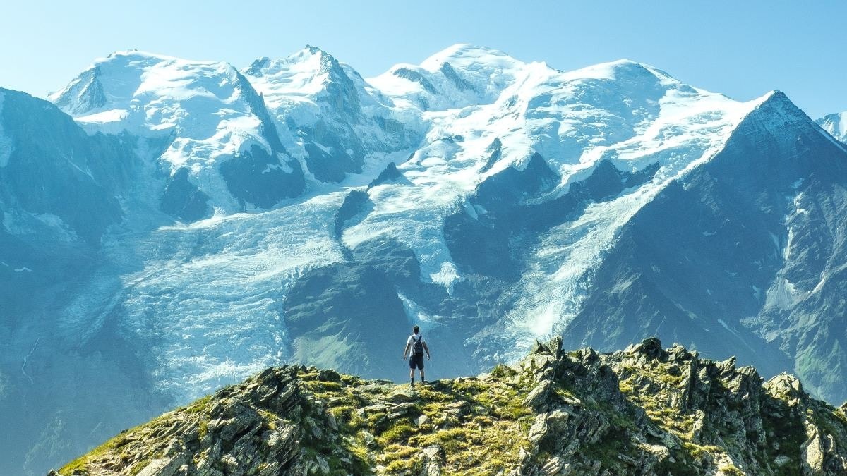 Man standing on mountain overlooking snowcapped mountains in Chamonix.