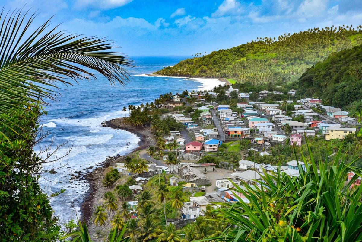 Small village along the ocean surrounded by green hills on a sunny day in St. Vincent