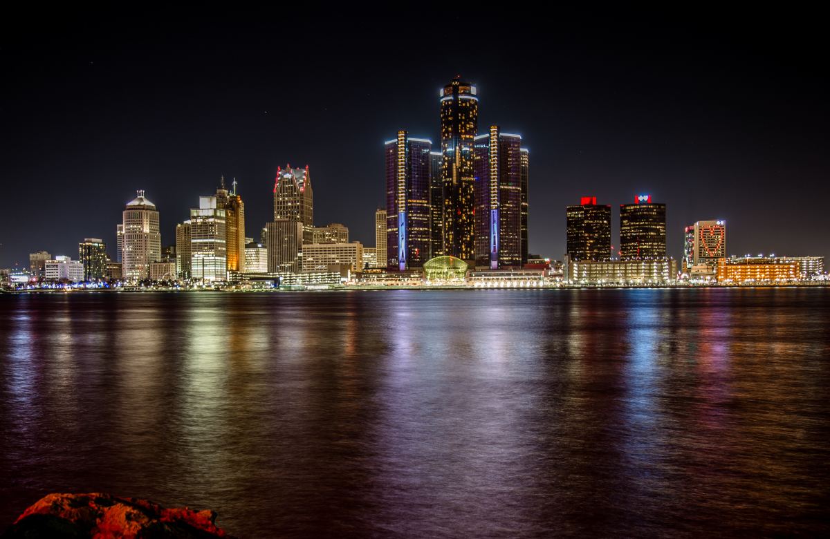 a view of the water and lit-up buildings of Detroit
